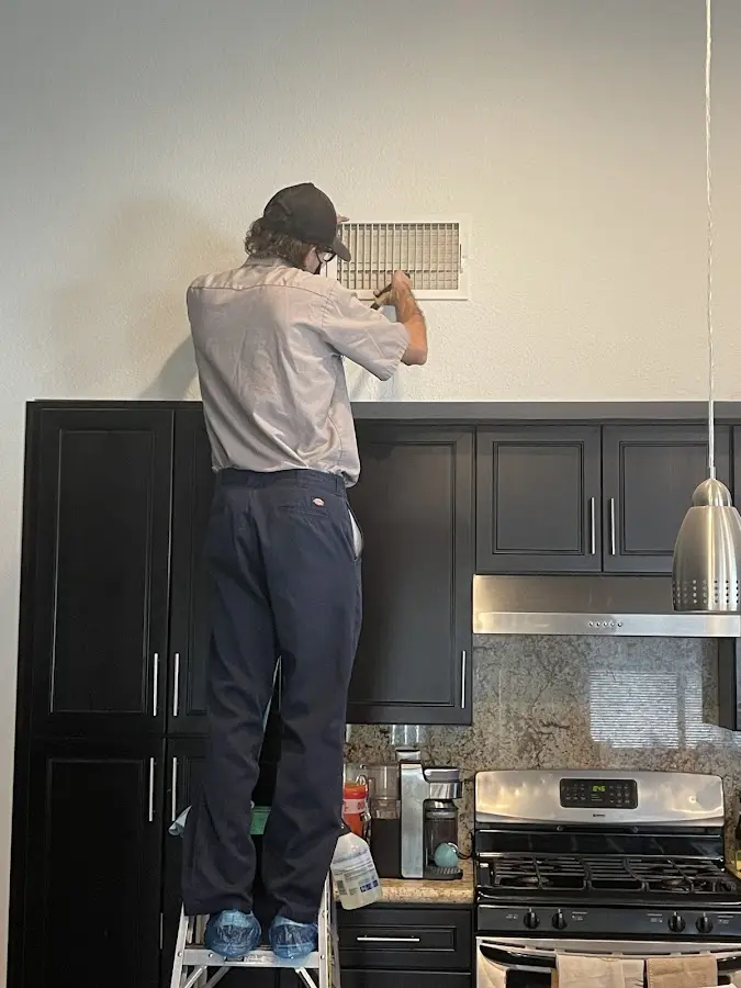 Technician inspecting an air vent during HVAC service in Van Buren